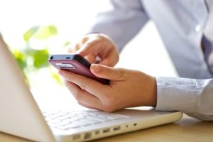 Person-using-Smart-Phone-and-Laptop-min